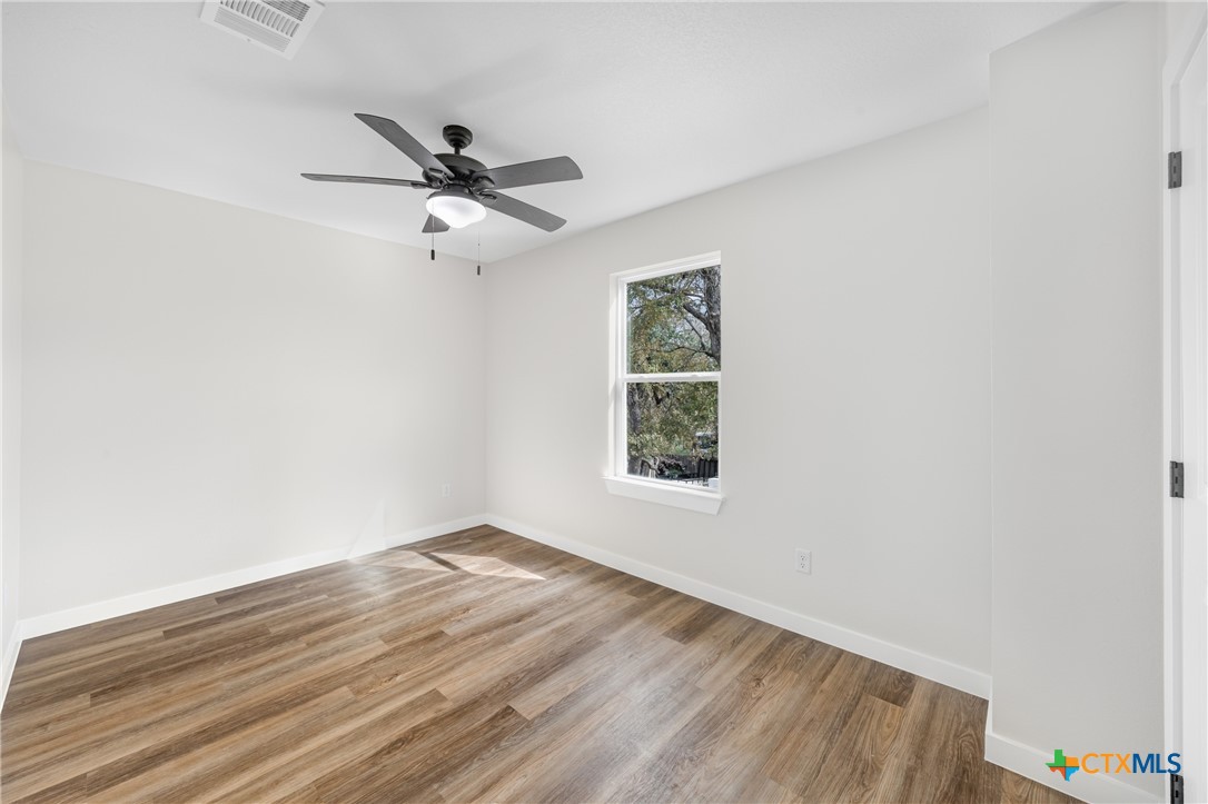 711 South 28th Street Temple, TX 76501 - Photo 22 of 26 an empty room with wooden floor ceiling fan and windows