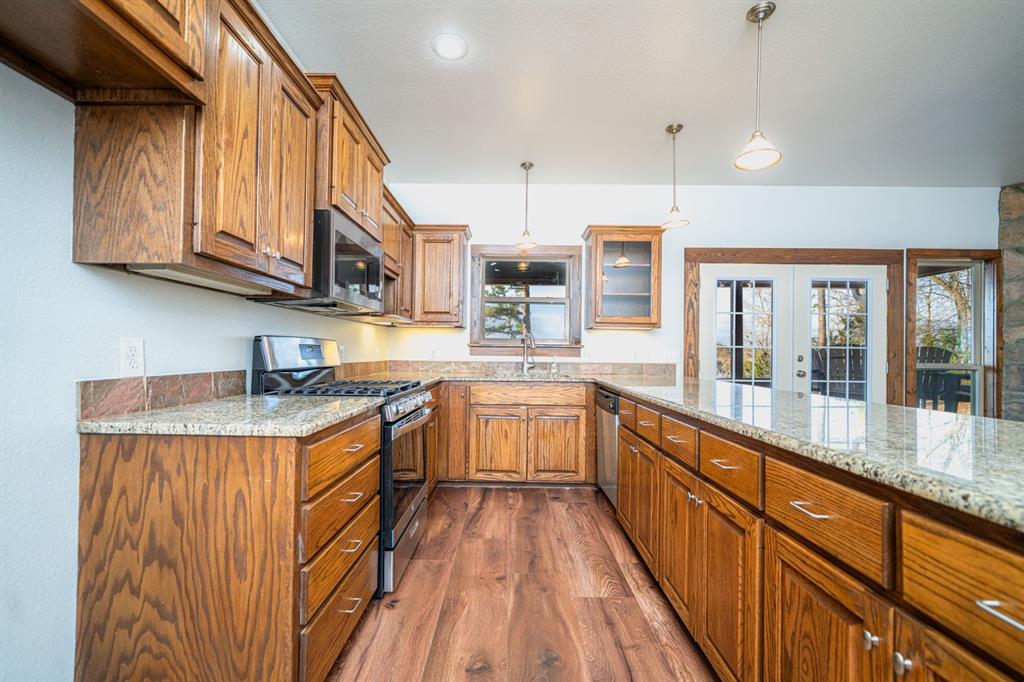 410 Private Road Leesburg, TX 75451 - Photo 13 of 38 a kitchen with stainless steel appliances granite countertop a stove a sink dishwasher and a refrigerator with wooden cabinets