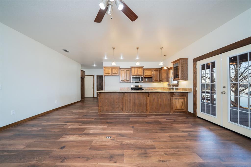 410 Private Road Leesburg, TX 75451 - Photo 9 of 38 a large white kitchen with kitchen island a stove a refrigerator cabinets and wooden floor