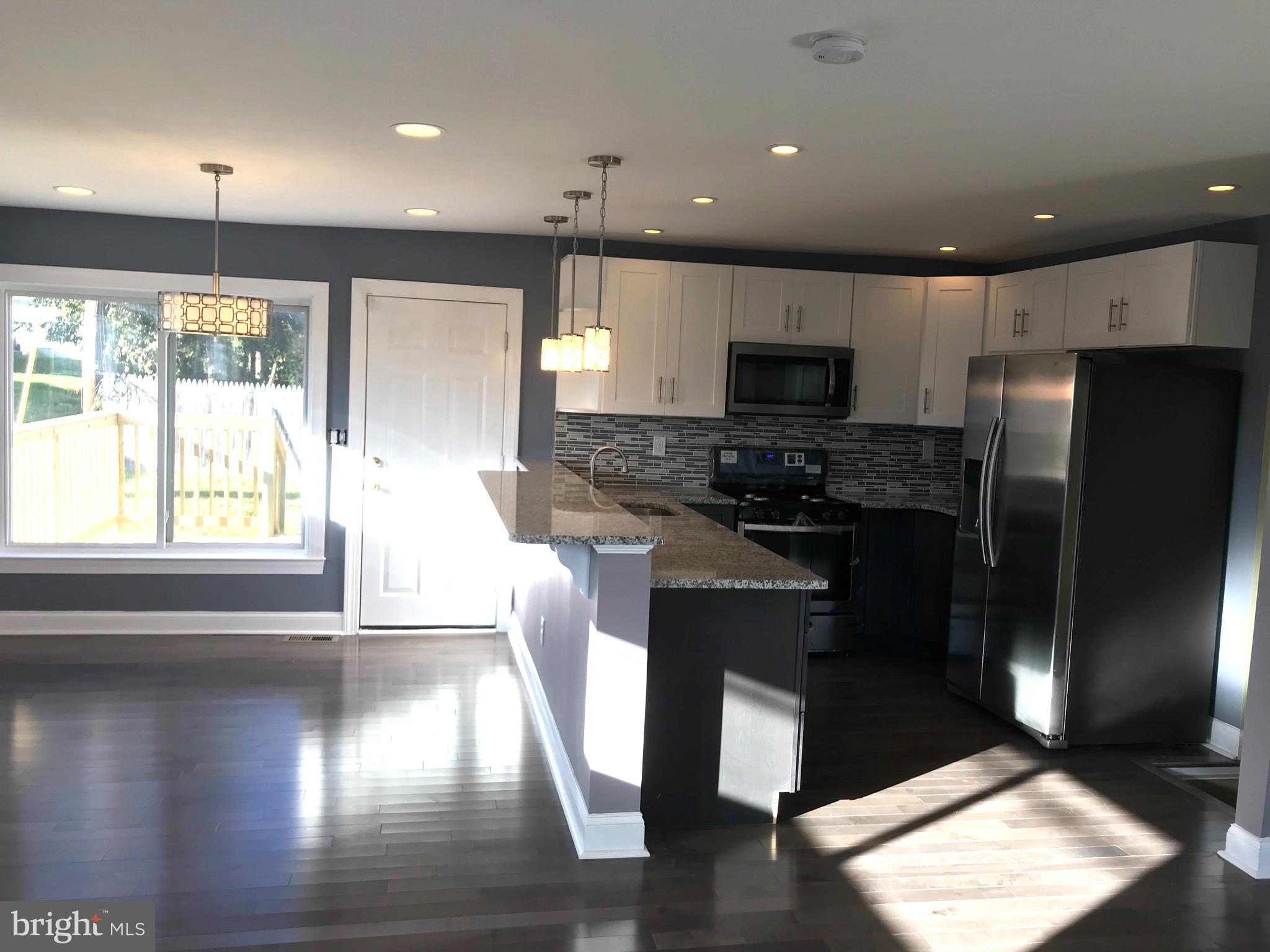 7806 Selgrave Road Baltimore, MD 21244 - Photo 3 of 25 a kitchen with granite countertop a refrigerator and a stove top oven
