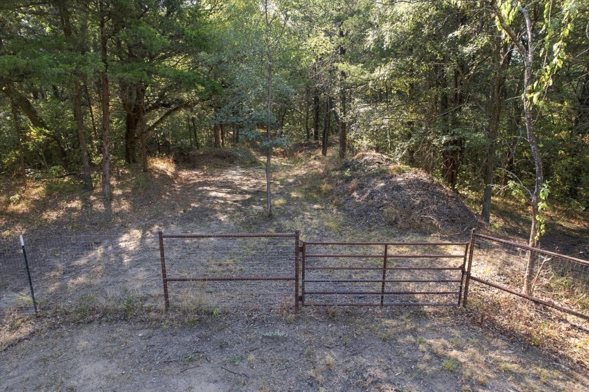 Bloomfield Road Colbert, OK 74733 - Photo 25 of 25 Expansive wooded terrain with mature trees and natural ground cover, featuring a metal gate entrance