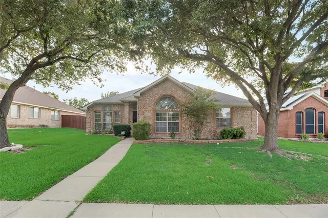 a front view of a house with a yard and trees