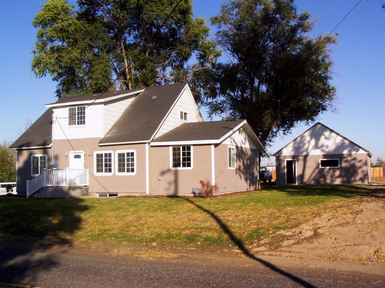 a view of a yard in front of a brick house with large windows