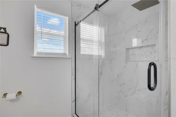 a bathroom with a tub shower and a window