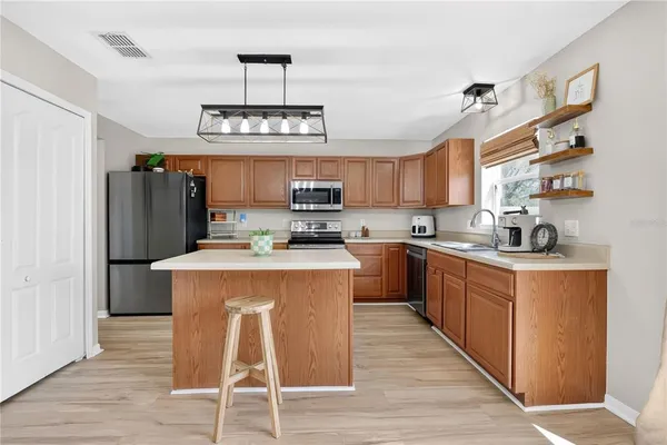 a kitchen with stainless steel appliances granite countertop a refrigerator a sink dishwasher a stove and a microwave oven with cabinets