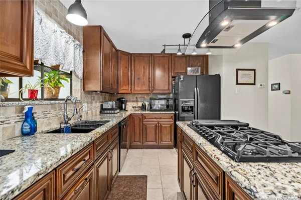 a kitchen with granite countertop a stove sink and refrigerator