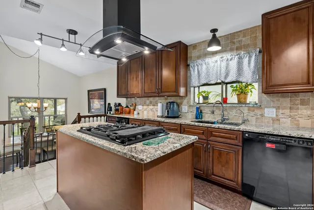 a kitchen with stainless steel appliances granite countertop a sink a stove and a wooden floors