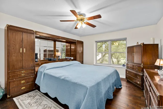a bedroom with a bed and dresser with wooden floor