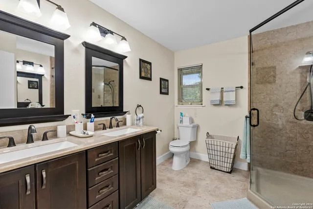 a bathroom with a double vanity sink toilet and mirror
