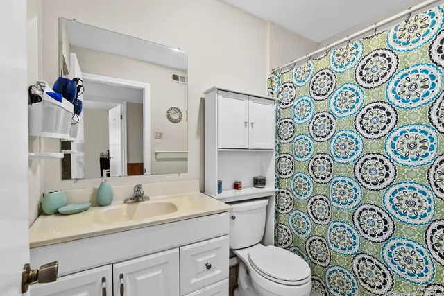 a bathroom with a toilet sink and mirror with shower curtain