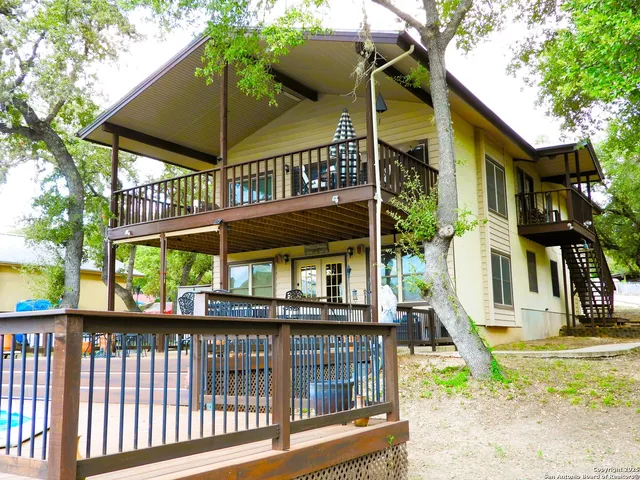a view of a brick house with a small yard and a deck