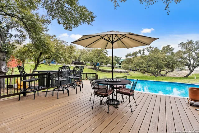 a view of a roof deck with table and chairs under an umbrella with wooden floor
