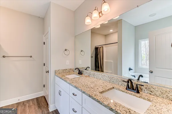 a bathroom with a granite countertop double vanity sink and a mirror