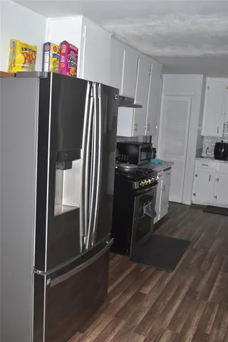 a kitchen with granite countertop a refrigerator and a stove top oven