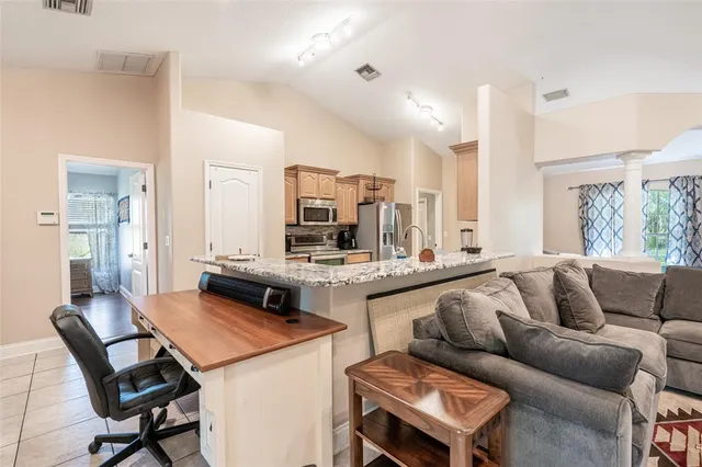 a living room with stainless steel appliances kitchen island granite countertop furniture and a large window
