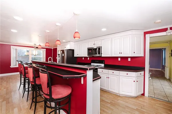 a kitchen with stainless steel appliances kitchen island granite countertop a table chairs stove and sink