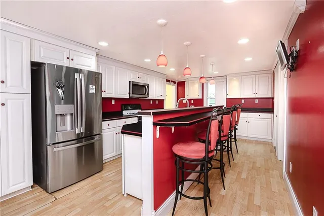 a kitchen with stainless steel appliances kitchen island granite countertop a refrigerator a stove top oven and a dining table with wooden floor