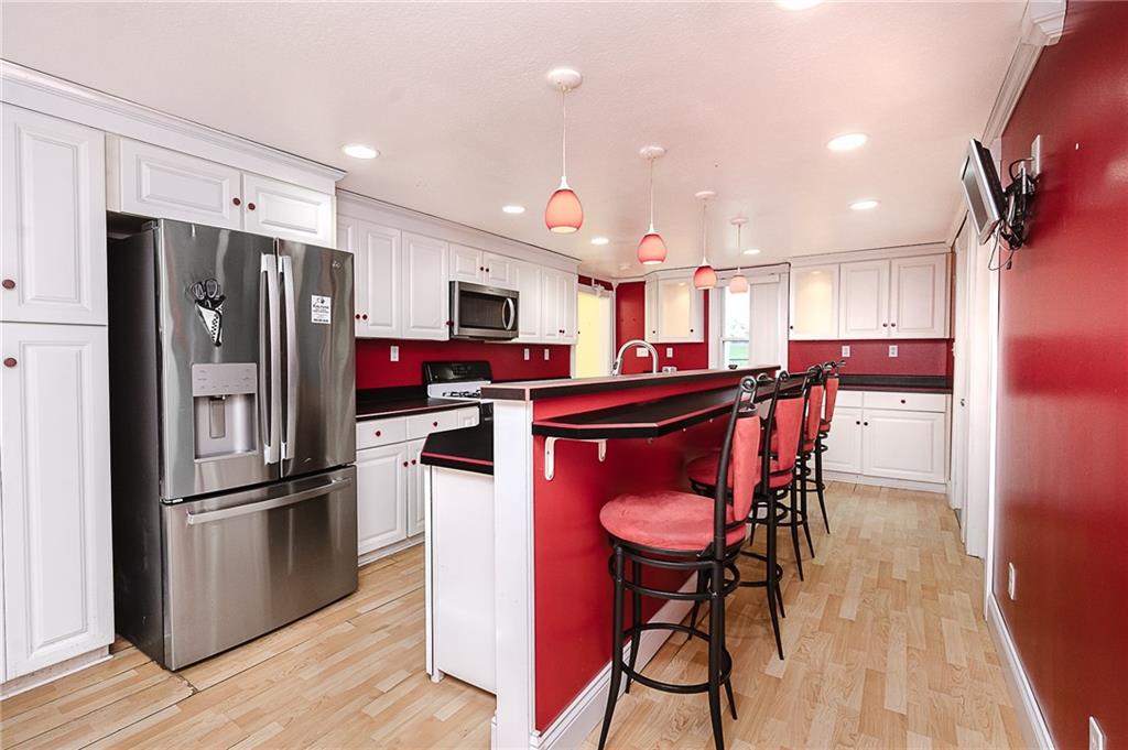 228 Harrison Avenue Robinson, PA 15949 - Photo 13 of 46 a kitchen with stainless steel appliances kitchen island granite countertop a refrigerator a stove top oven and a dining table with wooden floor