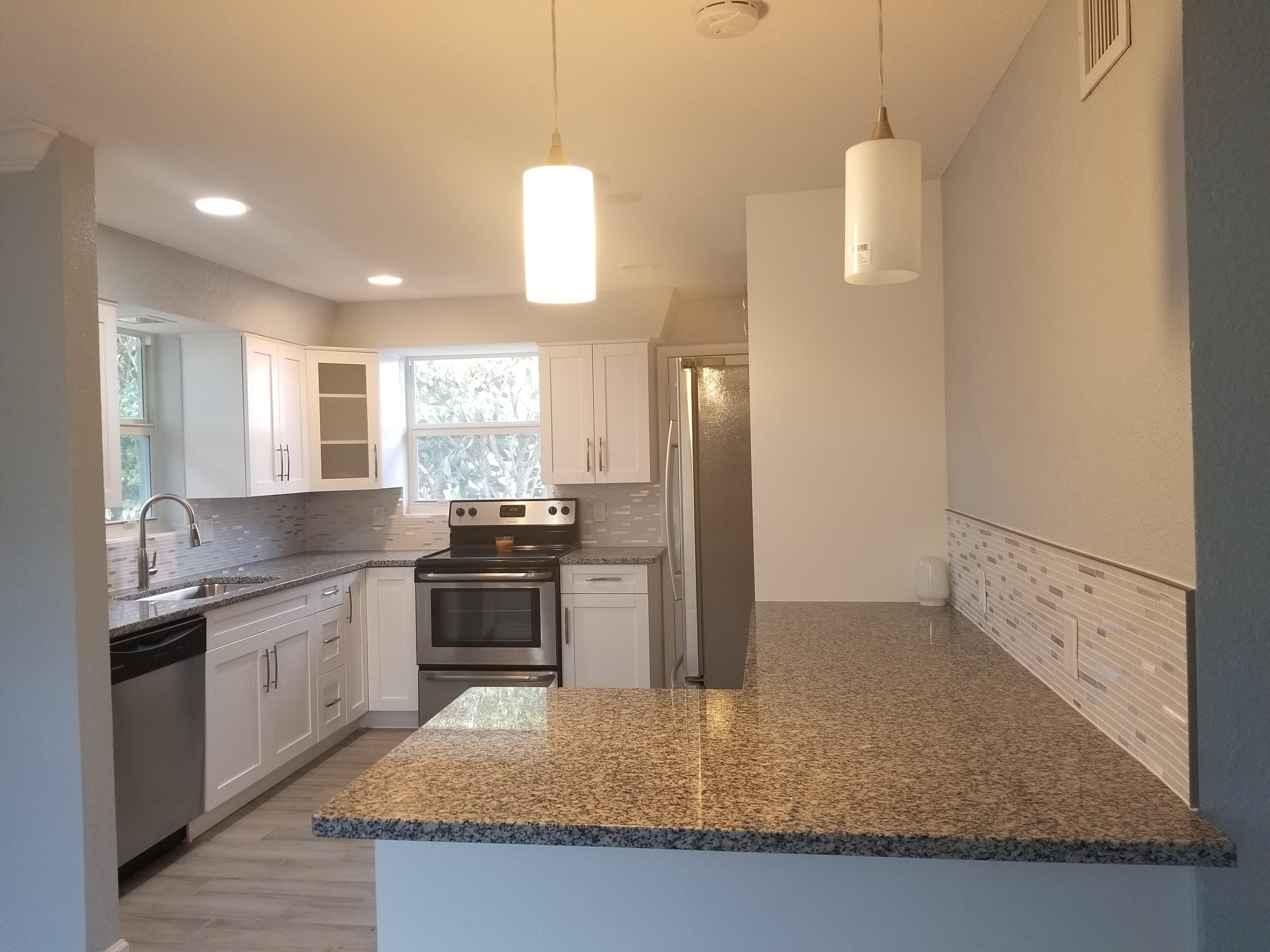 1221 Highview Road Lake Worth, FL 33462 - Photo 2 of 20 a kitchen with stainless steel appliances granite countertop a stove a sink and a refrigerator