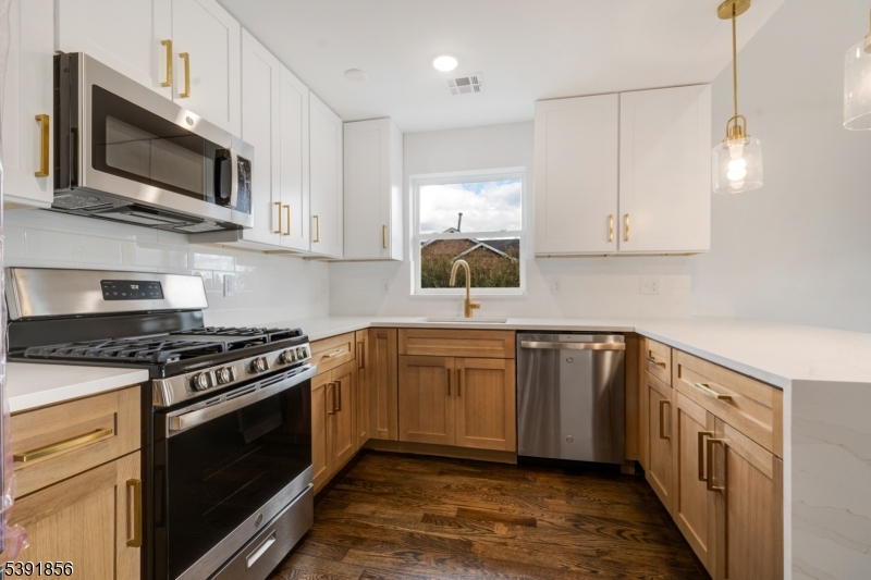 543 13th Avenue Newark, NJ 07103 - Photo 9 of 38 a kitchen with stainless steel appliances granite countertop a sink a stove and microwave