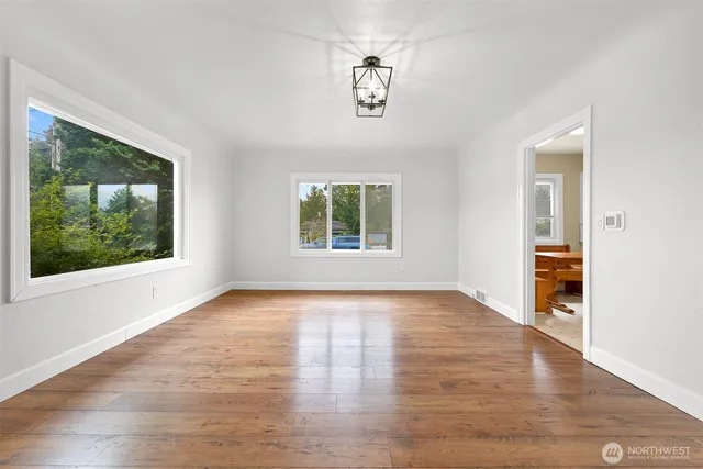 a view of an empty room with a window and wooden floor