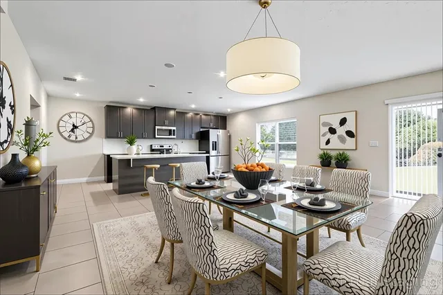 a living room with stainless steel appliances kitchen island a table and chairs in it