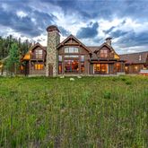 a view of a big house with a big yard and large trees