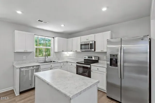 a kitchen with a refrigerator a sink a stove a microwave a center island and cabinets