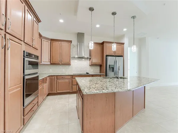 a kitchen with stainless steel appliances granite countertop a sink refrigerator and cabinets