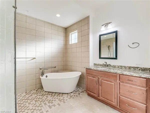 a spacious bathroom with a bathtub sink and mirror