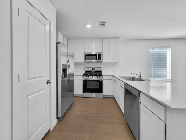 a kitchen with granite countertop a refrigerator and a stove top oven