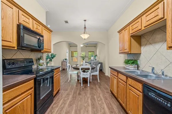 a kitchen with stainless steel appliances a kitchen island hardwood floor sink stove dining table and chairs