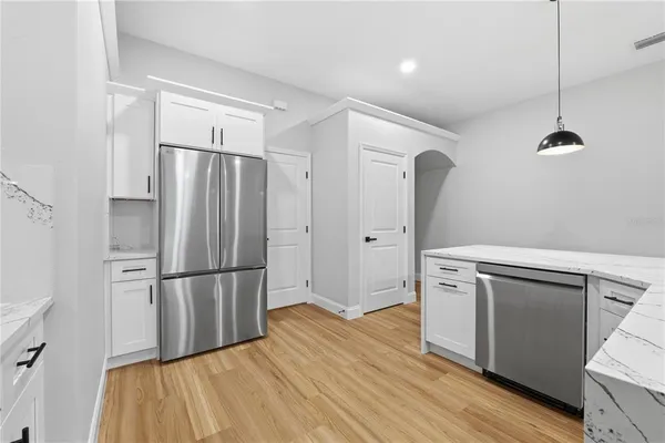 a kitchen with granite countertop a refrigerator and a wooden floor