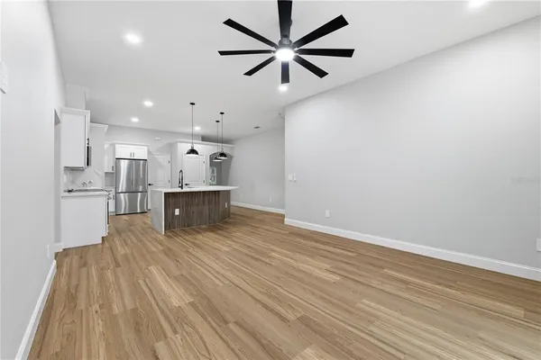 a living room with stainless steel appliances kitchen island hardwood floor and a ceiling fan