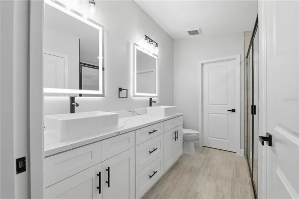a spacious bathroom with a double vanity sink a mirror and a