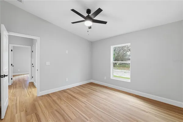 an empty room with wooden floor and windows