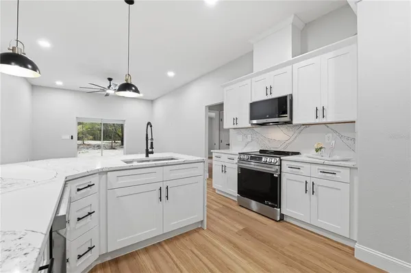 a kitchen with stainless steel appliances white cabinets a sink a stove a microwave and wooden floors