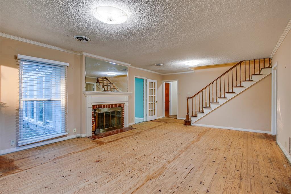 1439 Jr Drive Dallas, TX 75208 - Photo 5 of 39 a view of an empty room with wooden floor fireplace and a window