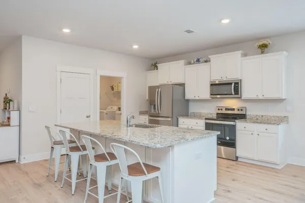 a kitchen with stainless steel appliances granite countertop a kitchen island hardwood floor and a sink