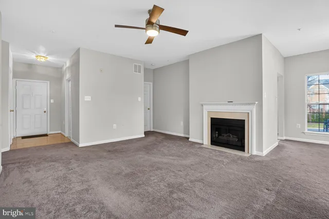 an empty room with windows and fireplace
