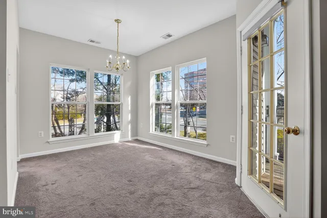 a view of an empty room with a window and chandelier