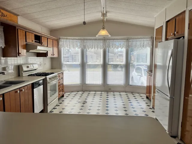 a kitchen with stainless steel appliances granite countertop a refrigerator a stove and a sink