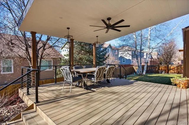 a view of a roof deck with table and chairs a barbeque with wooden floor and fence