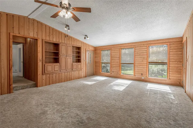 a view of an empty room with a window and a kitchen