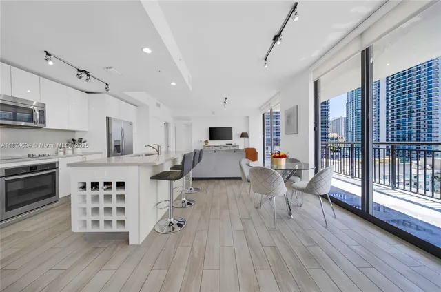 a kitchen with stainless steel appliances a stove a sink dishwasher a refrigerator white cabinets and wooden floor