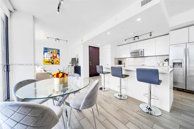 a kitchen with stainless steel appliances kitchen island dining table and wooden floor