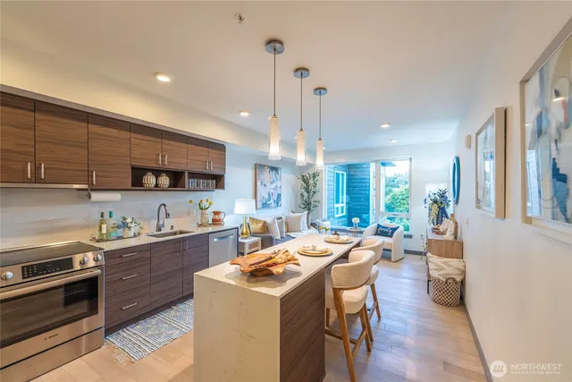 a kitchen with stainless steel appliances a stove a sink a refrigerator white cabinets and couches with wooden floor