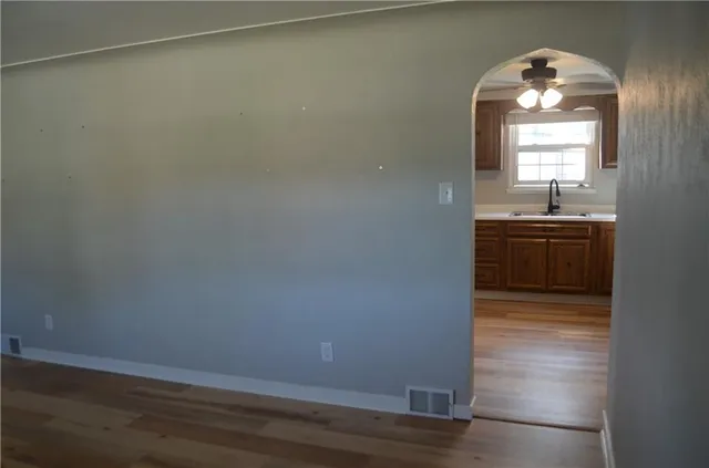 an empty room with wooden floor cabinet and windows
