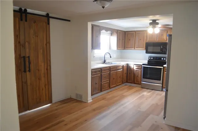 a kitchen with stainless steel appliances granite countertop a sink cabinets and wooden floor