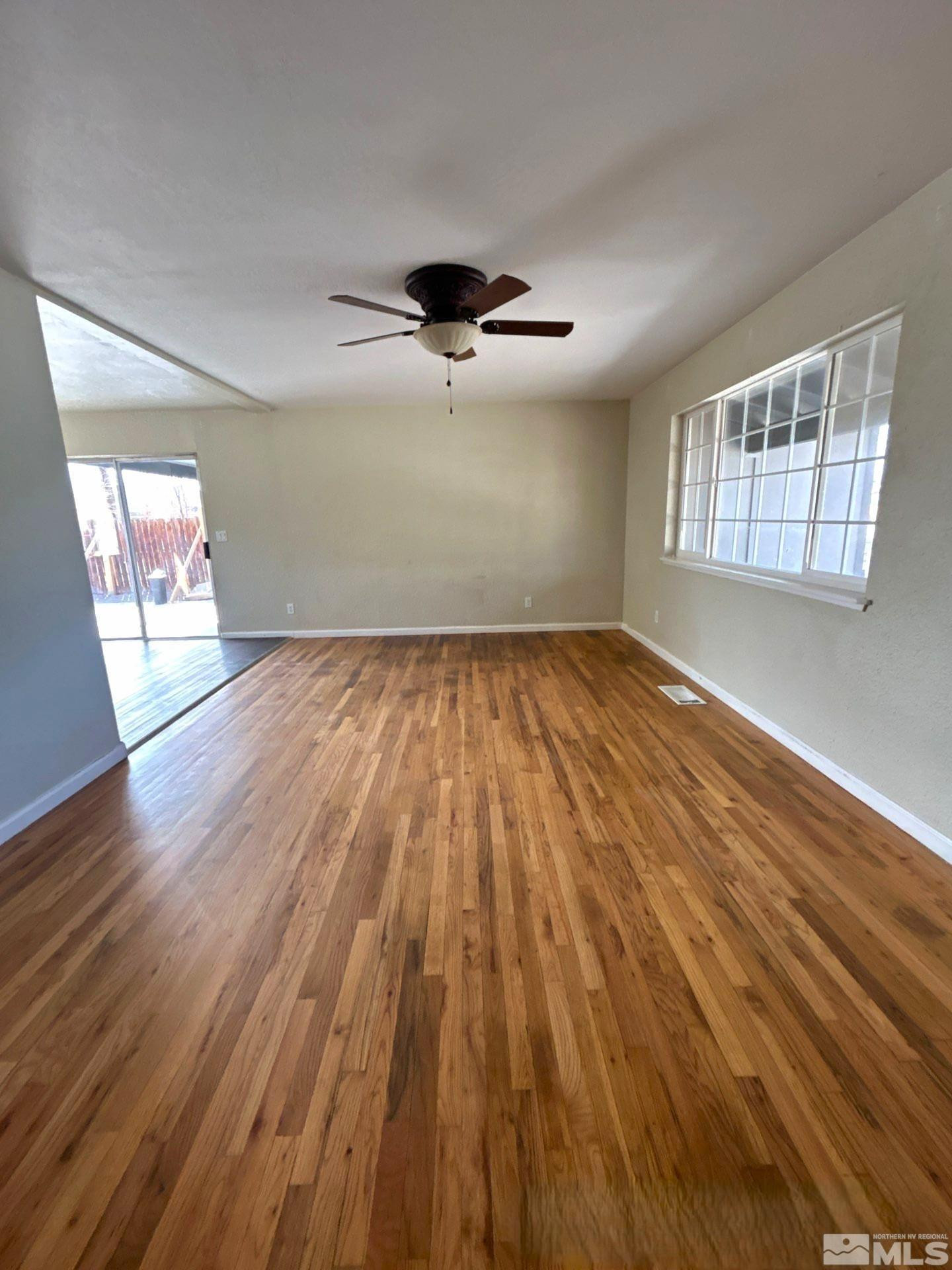 25 Comstock Drive Fernley, NV 89408 - Photo 2 of 10 an empty room with wooden floor chandelier fan and windows